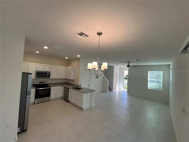 a kitchen with stainless steel appliances kitchen island granite countertop a stove top oven a sink dishwasher a dining table and chairs with wooden floor