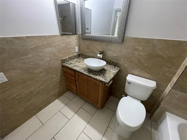 a bathroom with a granite countertop toilet sink and mirror