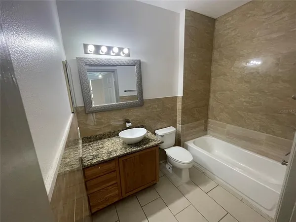 a bathroom with a granite countertop sink a toilet a mirror and bathtub