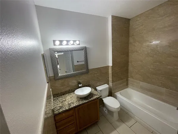 a bathroom with a granite countertop sink toilet a mirror and bathtub