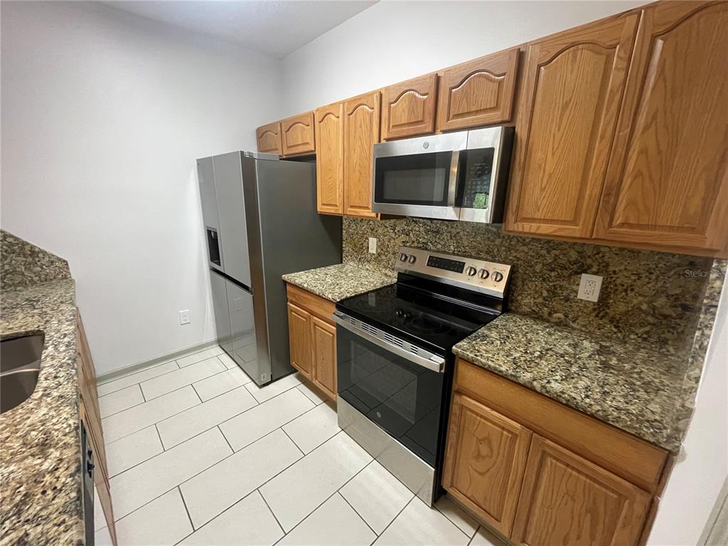 13548 Turtle Marsh Loop, Unit 427 Orlando, FL 32837 - Photo 2 of 34 a kitchen with stainless steel appliances granite countertop a stove a sink and a microwave
