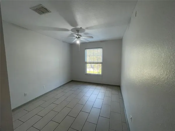 an empty room with windows and fan