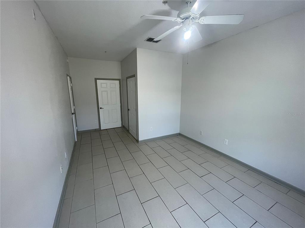13548 Turtle Marsh Loop, Unit 427 Orlando, FL 32837 - Photo 8 of 34 an empty room with a ceiling fan and carpet