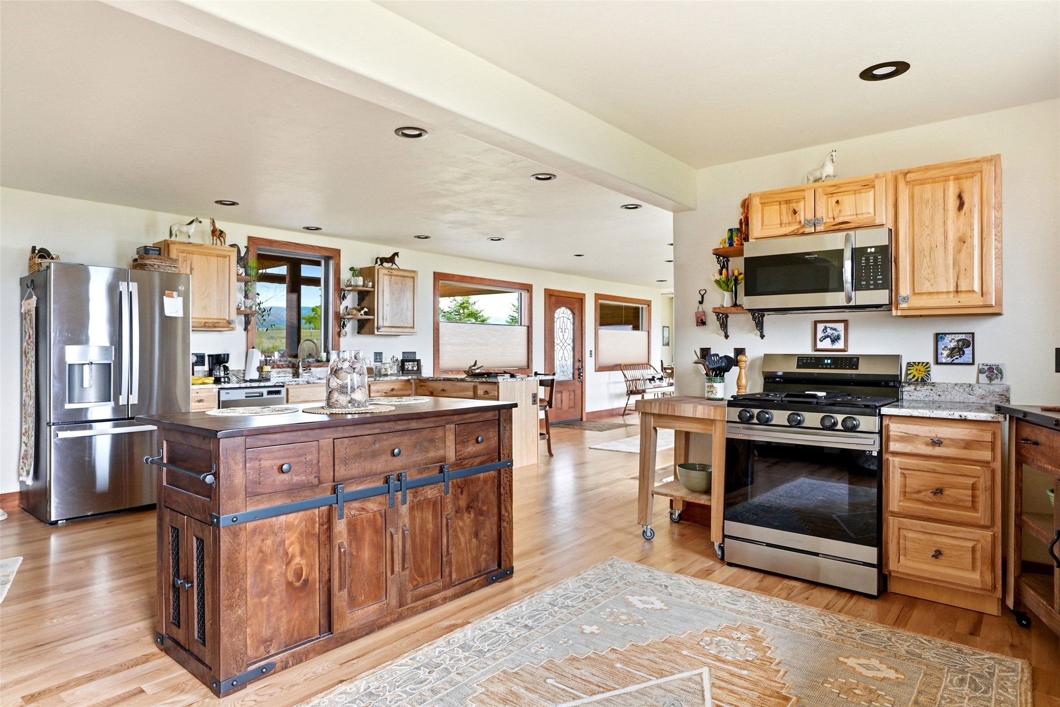 679 Hidden Valley Road North Florence, MT 59833 - Photo 28 of 85 Spacious kitchen featuring wood-finish flooring, a substantial wood island with barn door style cabinetry, stainless steel appliances, natural wood cabinetry, and recessed lighting