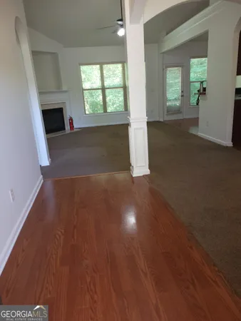 an empty room with windows fireplace and wooden floor