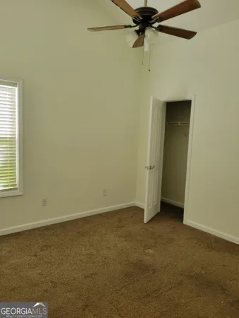 an empty room with a ceiling fan and a window
