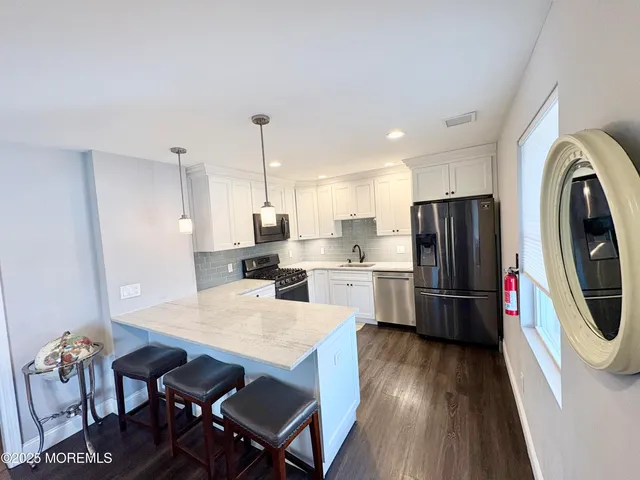 a kitchen with stainless steel appliances a dining table chairs stove refrigerator and wooden floor