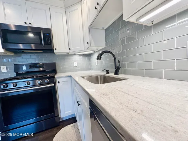 a kitchen with stainless steel appliances a stove a microwave a sink and cabinets
