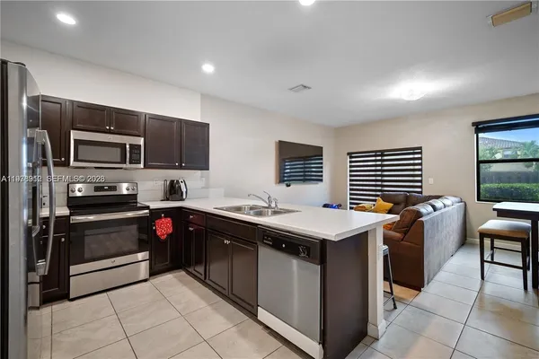 a kitchen with stainless steel appliances granite countertop a stove top oven a sink dishwasher and a refrigerator