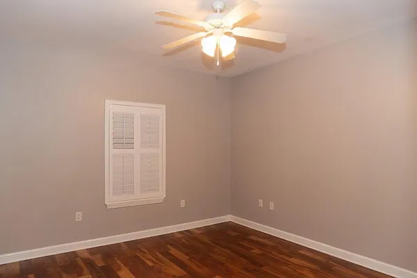 a view of an empty room with wooden floor and a bathroom
