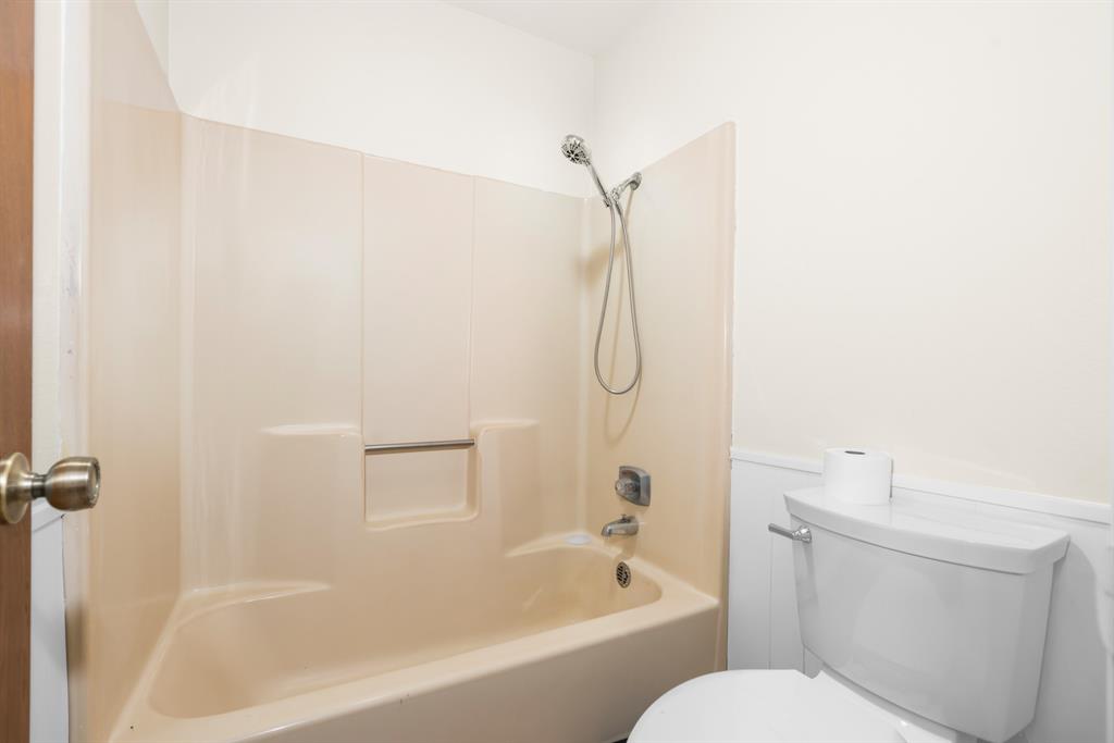 616 South Files Street Itasca, TX 76055 - Photo 25 of 37 a bathroom with a granite countertop bathtub shower sink vanity and toilet