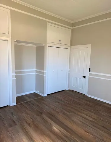 a view of an empty room with closet and wooden floor