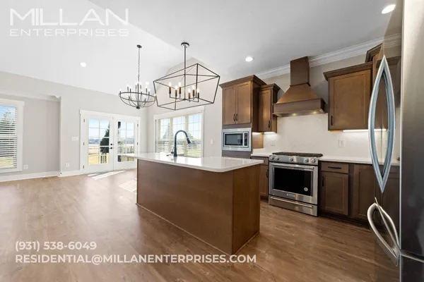 a kitchen with stainless steel appliances granite countertop a stove a sink a refrigerator and a wooden floors