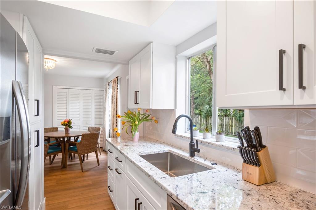 1275 7th Avenue North, Unit 201 Naples, FL 34102 - Photo 14 of 39 Kitchen featuring stainless steel fridge with ice dispenser, decorative backsplash, white cabinets, and light stone countertops