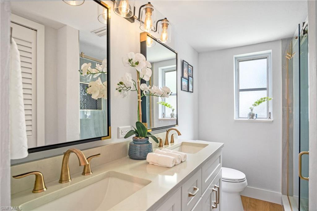 1275 7th Avenue North, Unit 201 Naples, FL 34102 - Photo 20 of 39 Full bathroom with double vanity, a shower with shower door, and wood finished floors
