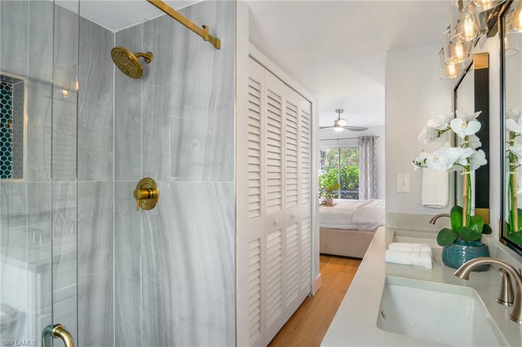 1275 7th Avenue North, Unit 201 Naples, FL 34102 - Photo 22 of 39 Ensuite bathroom with a stall shower, double vanity, wood finished floors, a closet, and ceiling fan