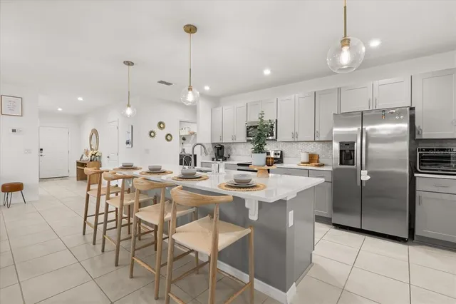a kitchen with stainless steel appliances kitchen island granite countertop a table chairs and a refrigerator