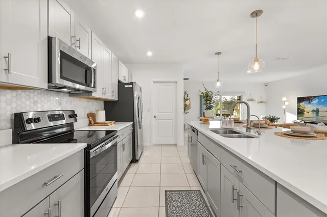 a kitchen with stainless steel appliances granite countertop a sink a stove top oven a refrigerator and white cabinets