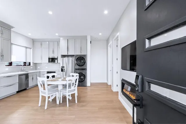 a living room with stainless steel appliances furniture a fireplace a flat screen tv and kitchen view