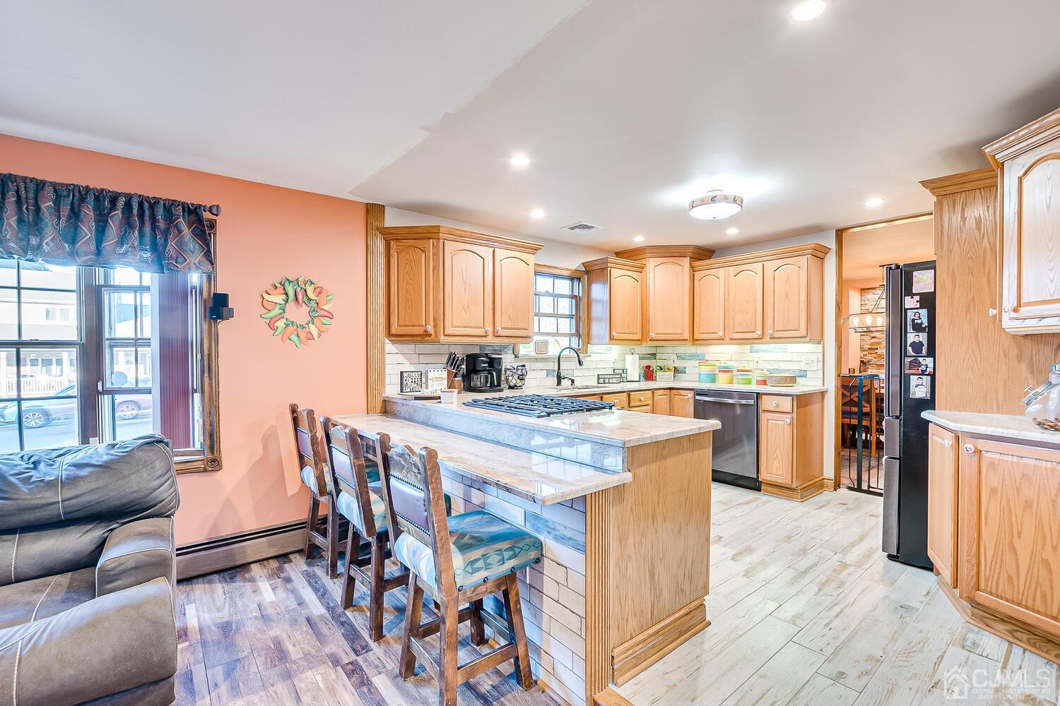 91 South Hill Road Colonia, NJ 07067 - Photo 14 of 46 a kitchen with stainless steel appliances kitchen island granite countertop a refrigerator a stove top oven and a dining table with wooden floor