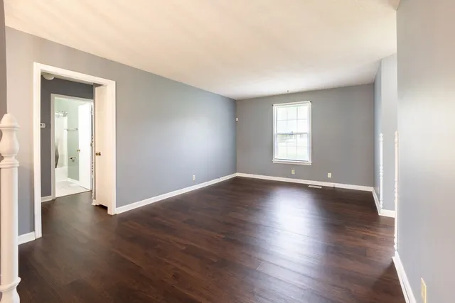 an empty room with wooden floor and window