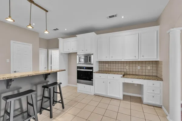 a kitchen with white cabinets and appliances