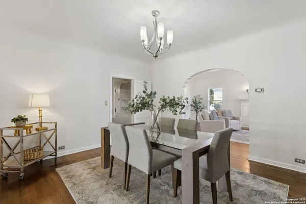 a dining room with wooden floor a chandelier a wooden table and chairs