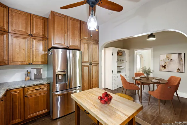 a kitchen with stainless steel appliances granite countertop a refrigerator a microwave oven a dining table and chairs with wooden floor