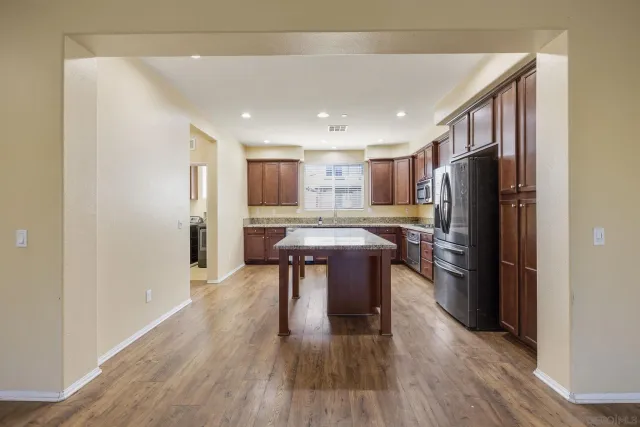 a kitchen with stainless steel appliances a refrigerator and a wooden floor