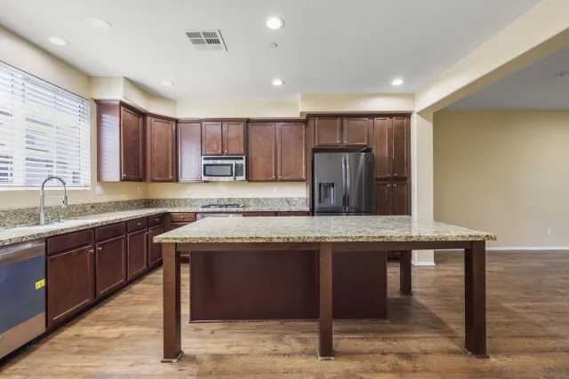 a kitchen with kitchen island granite countertop wooden floor window and cabinets