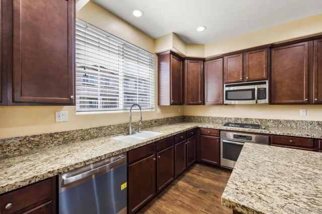 a kitchen with stainless steel appliances granite countertop hardwood floor sink stove microwave and cabinets