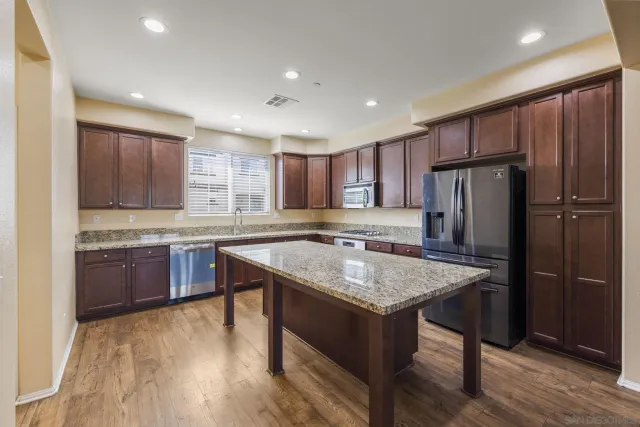 a kitchen with stainless steel appliances granite countertop a table chairs sink refrigerator and cabinets
