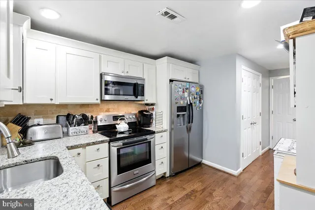 a kitchen with granite countertop a sink a stove and refrigerator