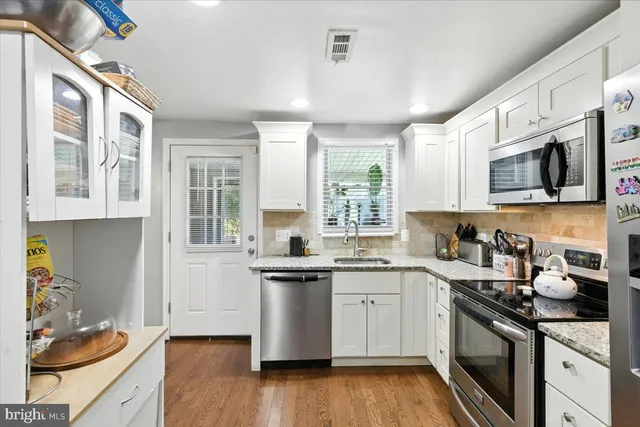 a kitchen with stainless steel appliances a sink dishwasher stove refrigerator and cabinets
