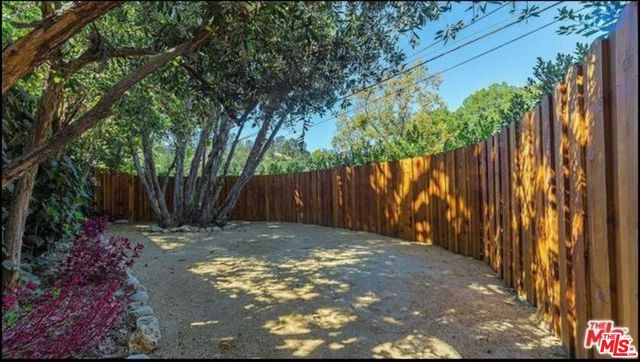 a view of a backyard with plants and wooden fence
