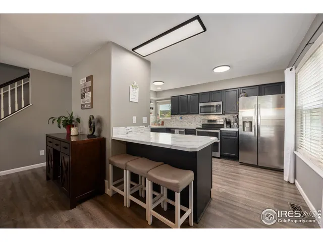a kitchen with kitchen island granite countertop a sink cabinets and stainless steel appliances