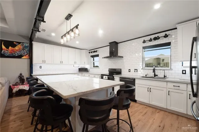 a kitchen with stainless steel appliances granite countertop a sink a stove a refrigerator and island with wooden floor