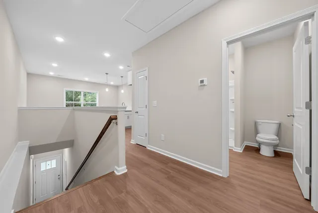 a view of a hallway with wooden floor and a bathroom