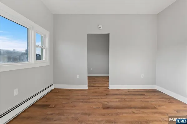 a view of an empty room with wooden floor and a window