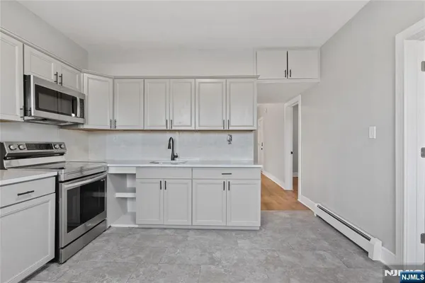 a kitchen with white cabinets stainless steel appliances and a sink