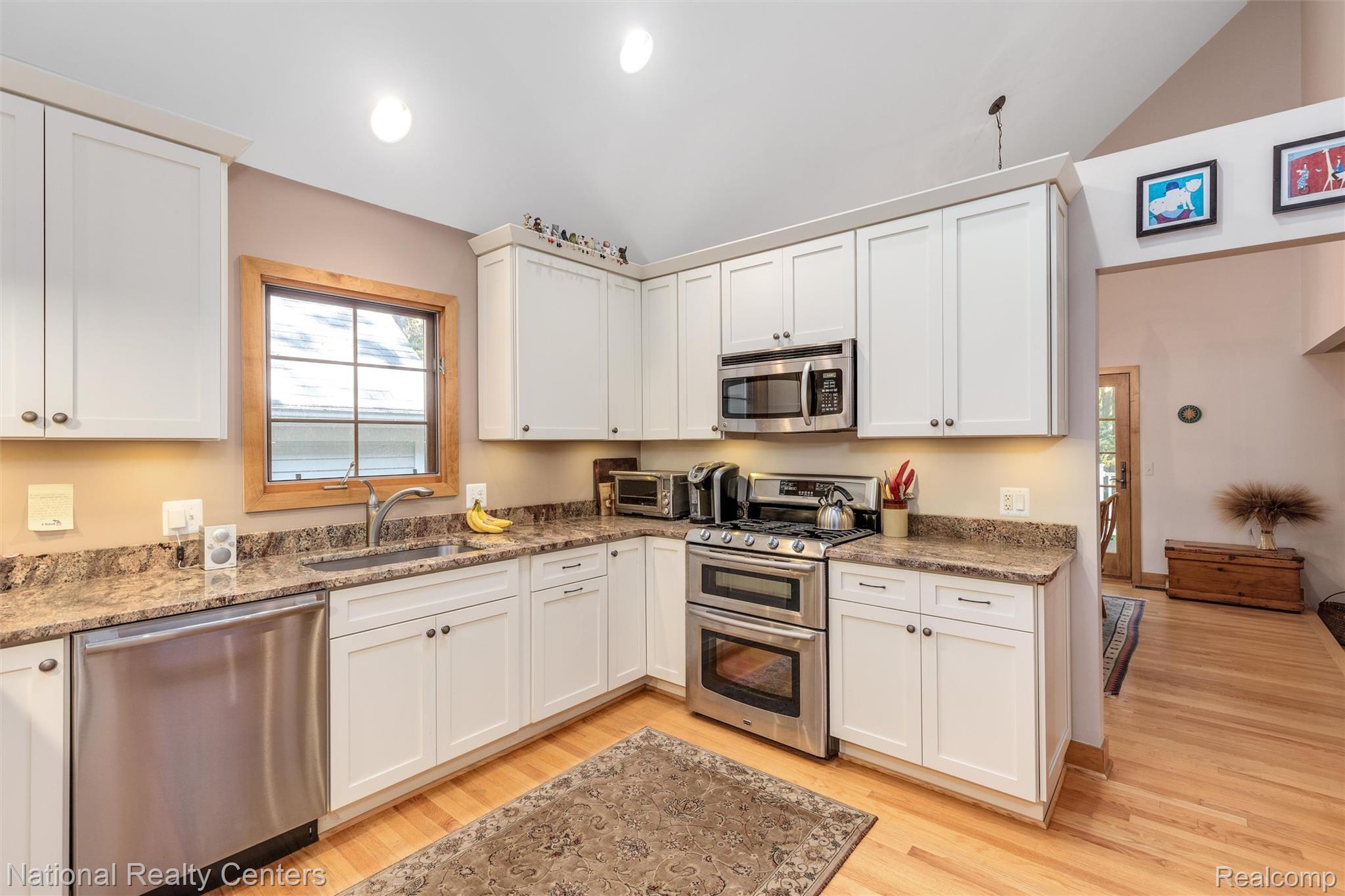 2322 Addaleen Road Highland, MI 48357 - Photo 7 of 54 Kitchen featuring appliances with stainless steel finishes, light stone counters, white cabinetry, lofted ceiling, and recessed lighting
