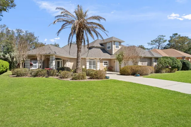 a view of a house with a big yard and palm trees