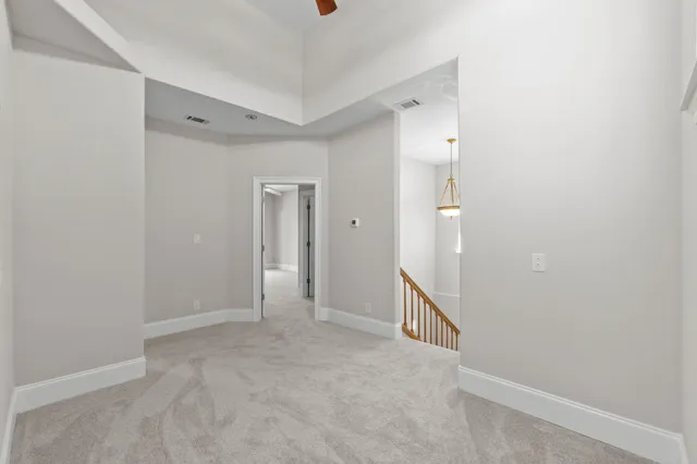 an empty room with chandelier fan and windows