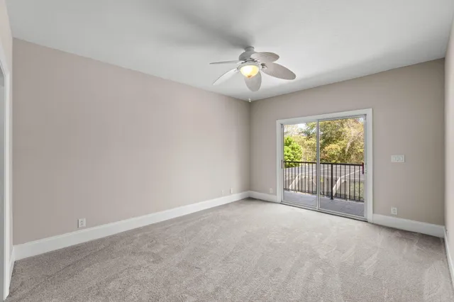 an empty room with a chandelier fan and windows