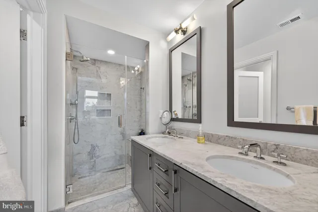 a bathroom with a granite countertop double vanity sink mirror and shower