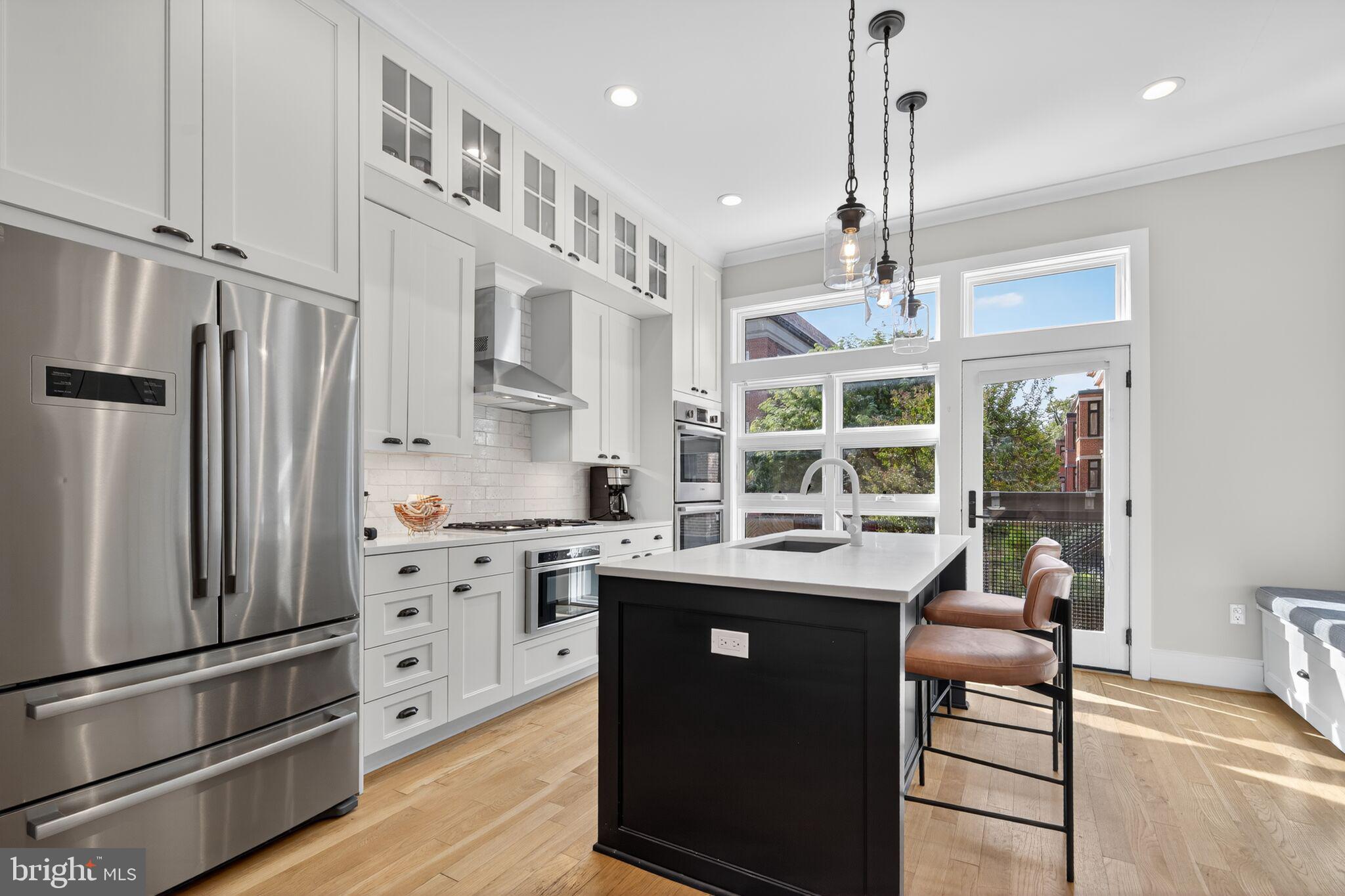 1309 D Street Southeast Washington, DC 20003 - Photo 8 of 38 a kitchen with stainless steel appliances kitchen island granite countertop a refrigerator a oven and white cabinets with wooden floors