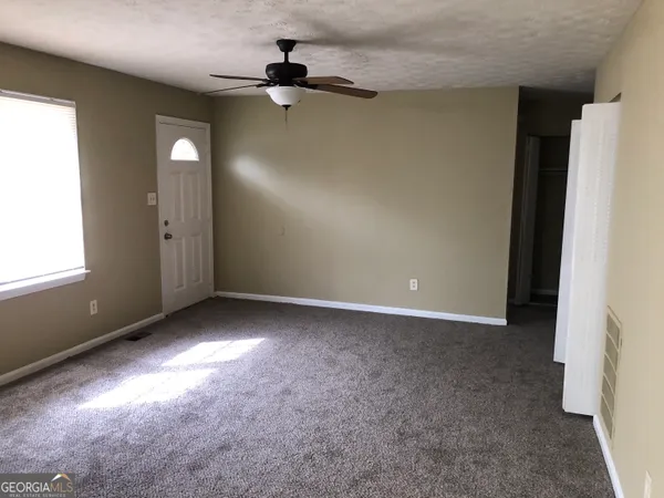 an empty room with windows and fan