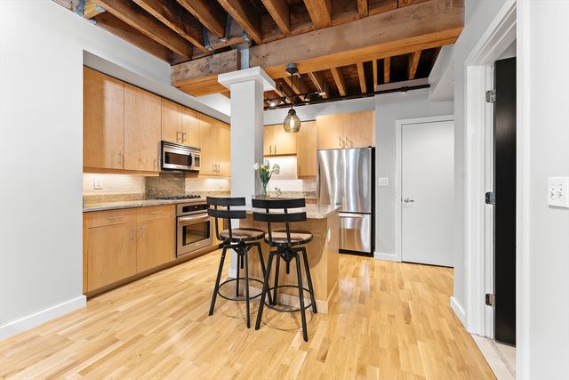 a kitchen with stainless steel appliances a table chairs refrigerator and microwave