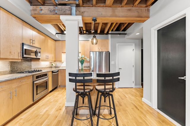 a kitchen with stainless steel appliances kitchen island granite countertop a table chairs sink and cabinets