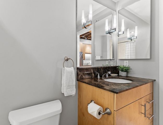 a bathroom with a granite countertop sink a toilet and mirror